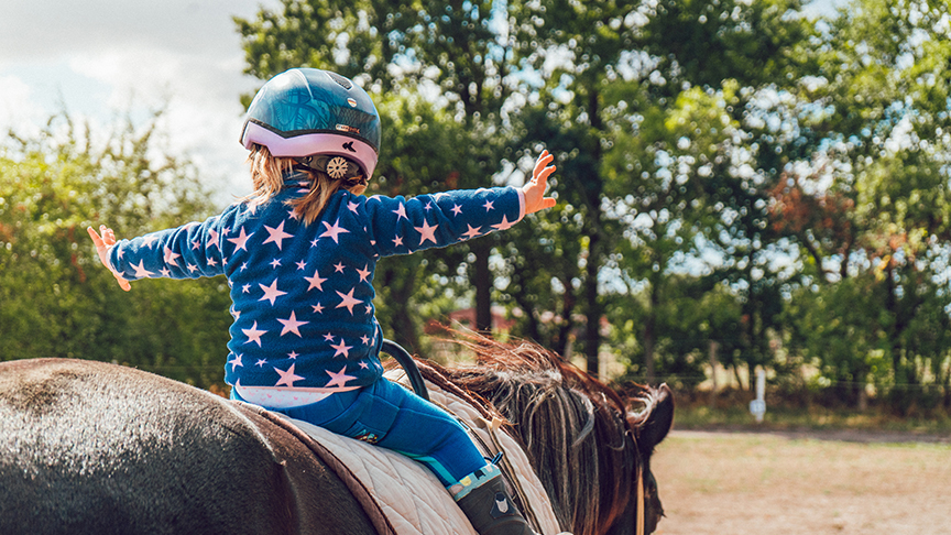 Child rides a horse for therapeutic riding