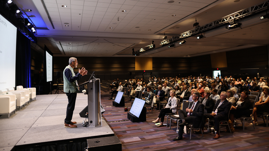 An indoor image of Dr. Patel, speaking to a full audience from onstage during the Fraser Mustard lecture.