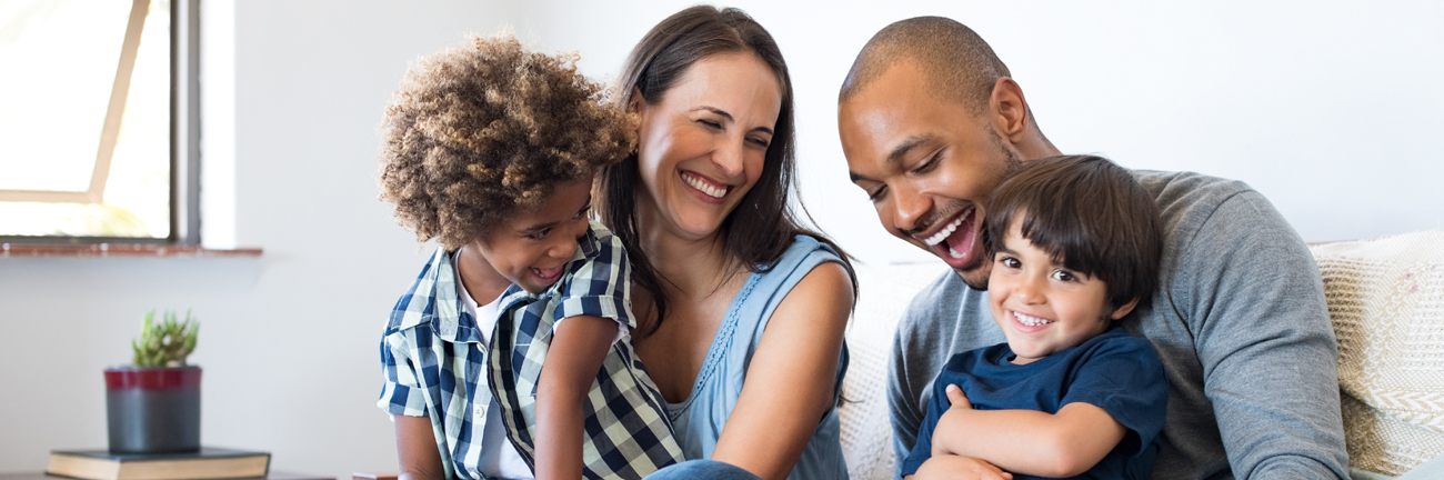 Happy multiethnic family sitting on sofa laughing together.