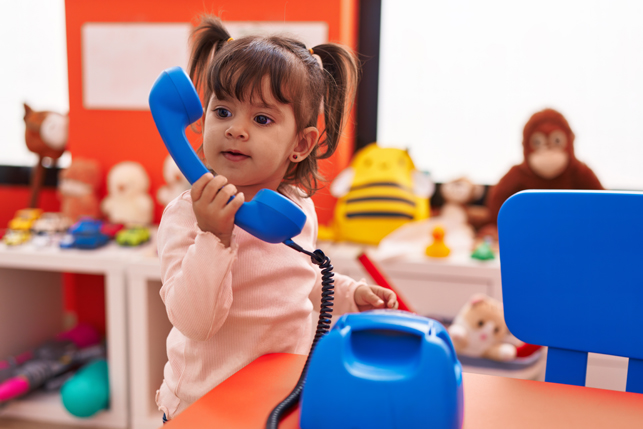 A toddler plays with a toy telephone.
