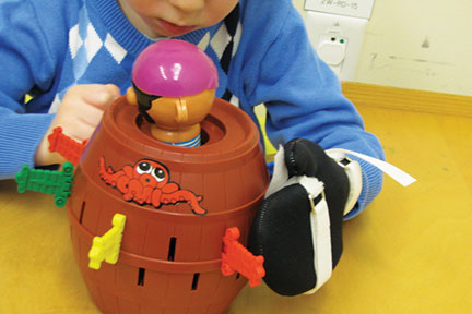 A young child plays with a toy while wearing a glove on one hand during a constraint-induced movement therapy (CIMT) session.