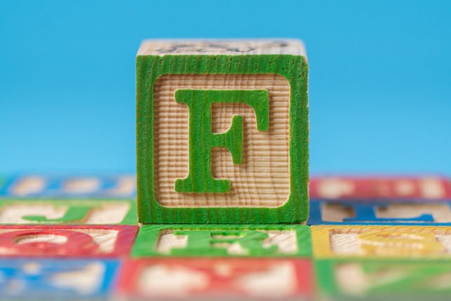 A child’s building block with the letter F on one of its faces.