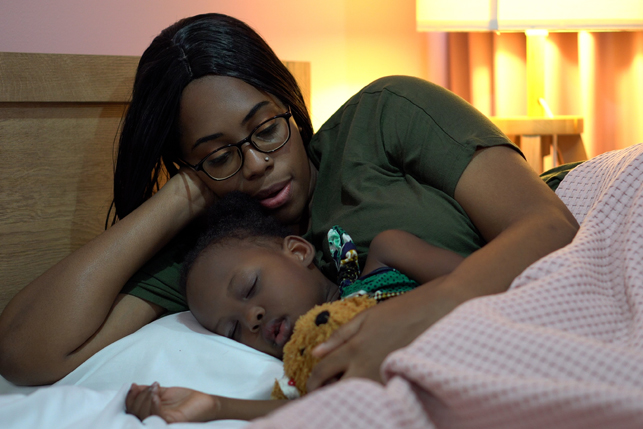 A parent soothes her child to sleep.