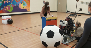 A child uses a BCI cap to propel an electric wheelchair towards a ball