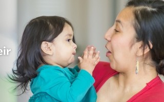 A mother in a red shirt lovingly holds her toddler, who touches her face. Text on the left reads, "Helping all kids live their best lives."